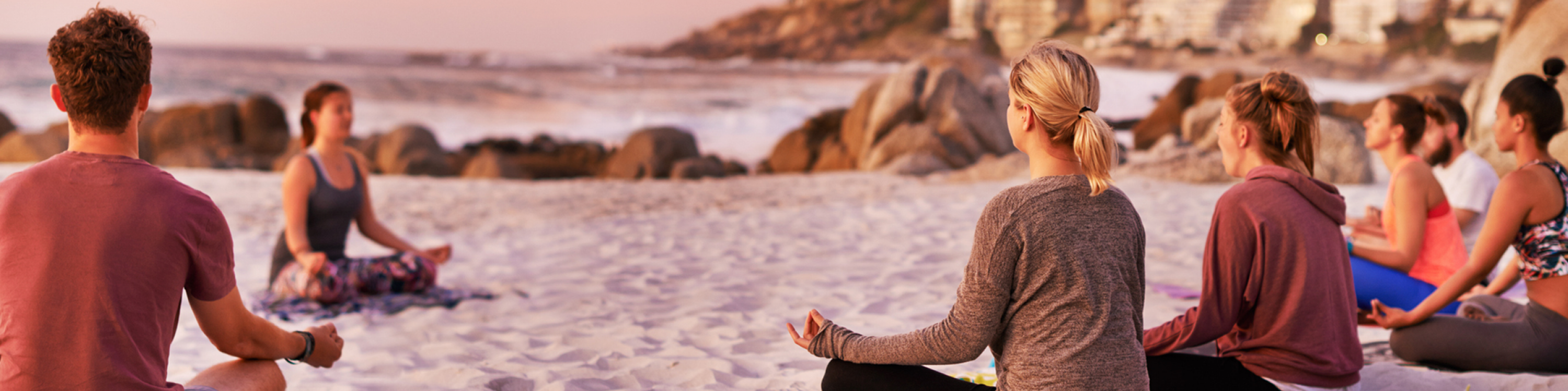 Shot of a group of people having a yoga session on the beach.